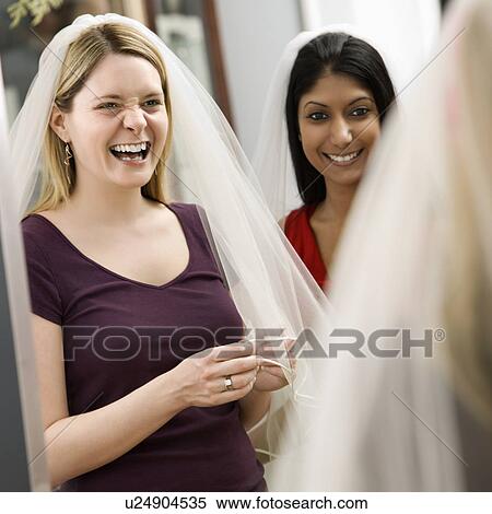 Indian woman and Caucasian woman trying on veils and looking in mirror. View Large Photo Image Stock Photography - Indian woman and Caucasian woman trying on veils and looking in mirror.. Fotosearch