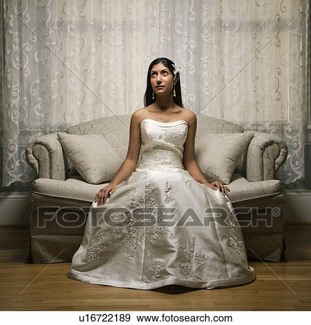 Stock Photo - Portrait of an Indian bride sitting on a love seat.. Fotosearch