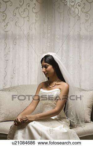 Stock Photograph - Portrait of an Indian bride sitting on a love seat.. Fotosearch