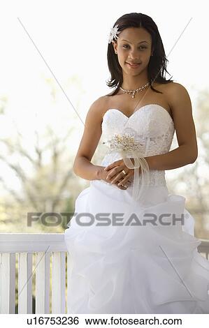 Stock Photograph - Portrait of bride leaning against railing. Fotosearch