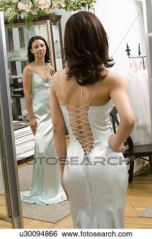Woman in a elegant evening gown looking in mirror View Large Photo Image Stock Photograph - Woman in a elegant evening gown looking in mirror. Fotosearch