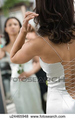 Stock Photo - Woman in evening gown looking at mirror. Fotosearch