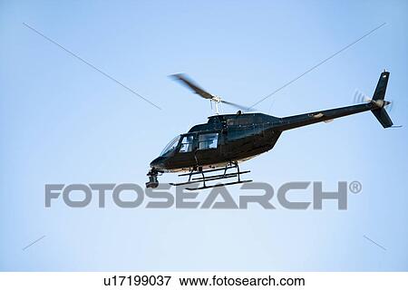 Helicopter flying through blue sky View Large Photo Image Stock Photo - Helicopter flying through blue sky. Fotosearch