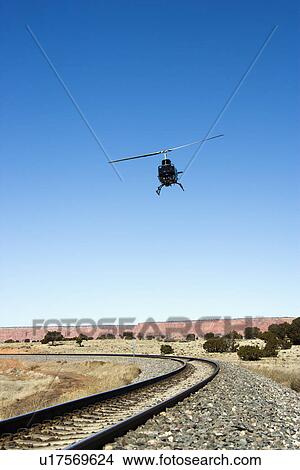 Low angle shot of helicopter flying over train tracks. View Large Photo Image Picture - Low angle shot of helicopter flying over train tracks.. Fotosearch