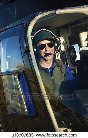 Stock Image - Portrait of helicopter pilot sitting in cockpit looking at viewer.. Fotosearch