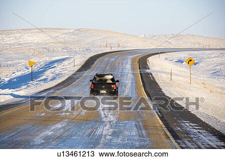 Stock Image - SUV on icy road in snowy landscape. Fotosearch