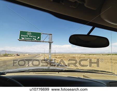 View from inside vehicle on desert highway with sign pointing towards Death Valley. View Large Photo Image Stock Photo - View from inside vehicle on desert highway with sign pointing towards Death Valley.. Fotosearch