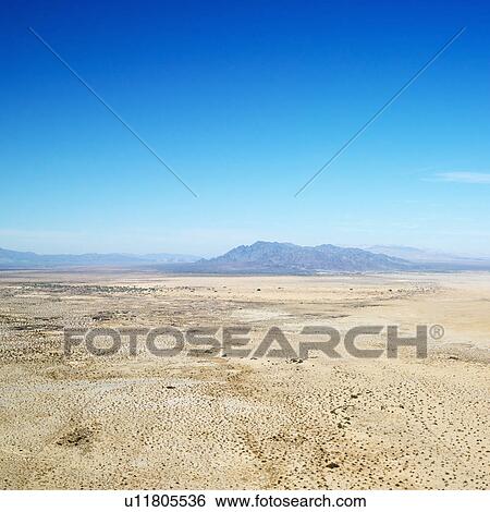 Stock Photograph - Aerial view of remote California desert with mountain range in background. Fotosearch