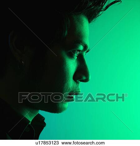Stock Image - Close up side view of attractive young man tinted green. Fotosearch