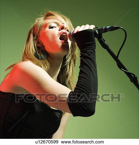 Female singing into a microphone View Large Photo Image Stock Photo - Female singing into a microphone. Fotosearch