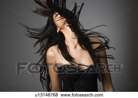 Stock Photo - Portrait of pretty young woman flinging long black hair into air.. Fotosearch