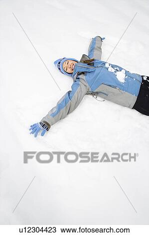 Attractive smiling mid adult Caucasian woman wearing blue ski clothing lying in snow with eyes closed making snow angel. View Large Photo Image Stock Image - Attractive smiling mid adult Caucasian woman wearing blue ski clothing lying in snow with eyes closed making snow angel.. Fotosearch