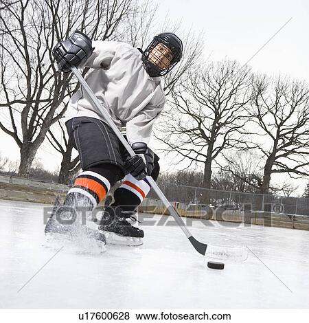 Boy in ice hockey uniform skating on ice rink moving puck View Large Photo Image Stock Photo - Boy in ice hockey uniform skating on ice rink moving puck. Fotosearch