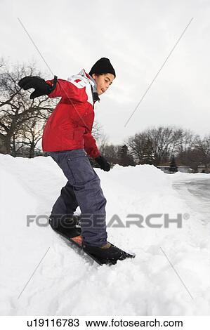Stock Image - Boy snowboarding in snow. Fotosearch