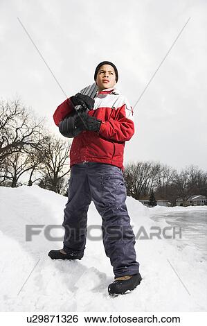 Stock Photograph - Boy standing holding snowboard in snow.. Fotosearch