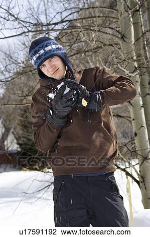 Stock Image - Male making snowball in winter setting. Fotosearch