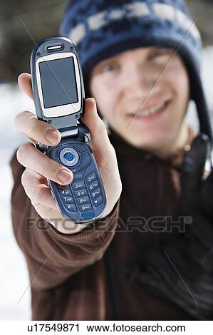 Stock Image - Male teenager holding out cellphone . Fotosearch