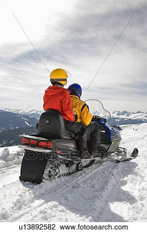 Man and woman riding on snowmobile in snowy mountainous terrain View Large Photo Image Stock Image - Man and woman riding on snowmobile in snowy mountainous terrain. Fotosearch