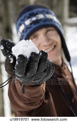 Stock Image - Man holding snowball out towards viewer.. Fotosearch