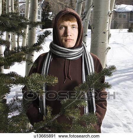 Stock Image - Portrait of a Caucasian male teenager wearing hoodie and scarf in winter setting.. Fotosearch