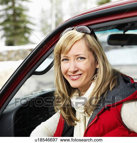 Stock Photo - Pretty woman sitting in vehicle wearing winter clothes in rural snowy Colorado smiling.. Fotosearch
