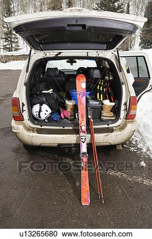 Stock Image - Rear view of automobile with back door open and ski equipment inside. Fotosearch