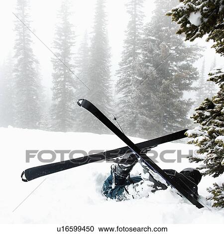 Stock Image - Skiers lying in snow near tree after crash in fog.. Fotosearch