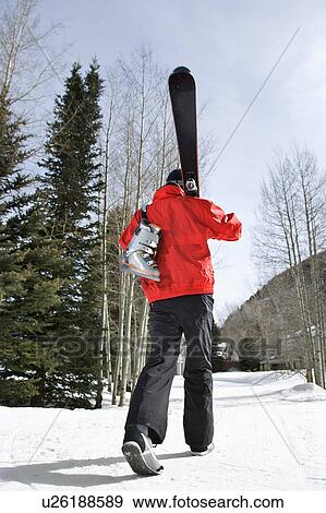 Stock Photo - Teenager walking and carrying ski gear.. Fotosearch