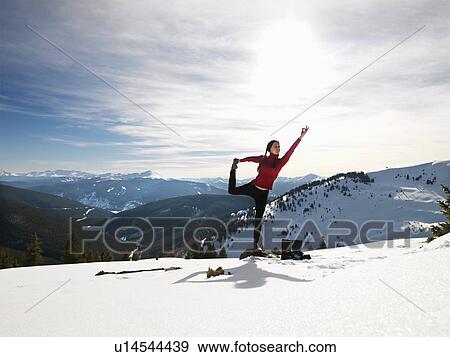 Woman doing yoga pose on rock in snow in mountainous terrain View Large Photo Image Stock Photo - Woman doing yoga pose on rock in snow in mountainous terrain. Fotosearch
