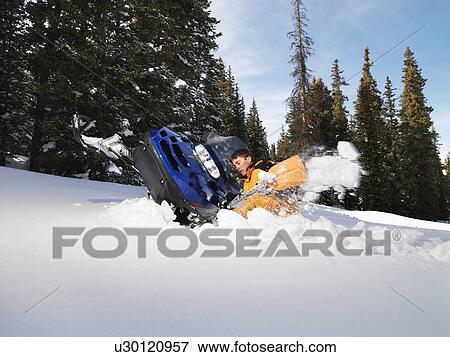 Young man digging out snowmobile submerged in the snow. View Large Photo Image Stock Photo - Young man digging out snowmobile submerged in the snow.. Fotosearch