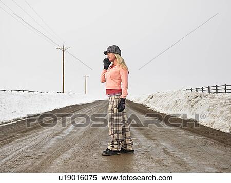 Young woman in winter clothes standing on muddy dirt road talking on cell phone. View Large Photo Image Stock Photography - Young woman in winter clothes standing on muddy dirt road talking on cell phone.. Fotosearch