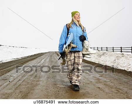 Young woman in winter clothes walking down muddy dirt road holding snowboard and boots smiling. View Large Photo Image Stock Image - Young woman in winter clothes walking down muddy dirt road holding snowboard and boots smiling.. Fotosearch