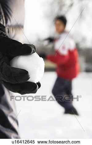 Boy holding snowball ready to throw at boy in background View Large Photo Image Stock Photography - Boy holding snowball ready to throw at boy in background. Fotosearch