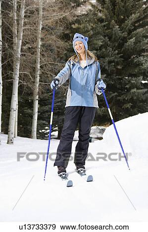 Stock Photo - Skier standing on ski slope smiling. Fotosearch