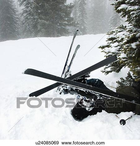 Stock Photo - Skiers lying in snow near tree after crash in fog. Fotosearch