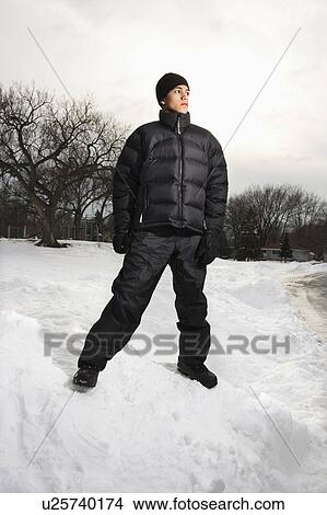 Picture - Teenage boy standing in snow wearing winter clothes.. Fotosearch