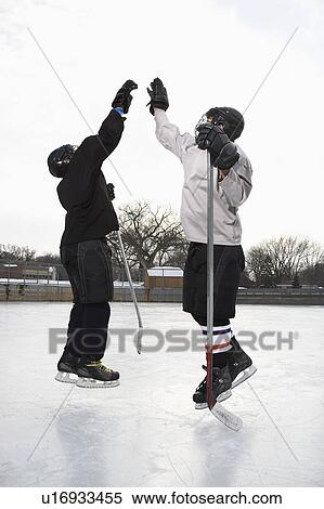 Two boys in ice hockey uniforms giving eachother high five on ice rink. View Large Photo Image Stock Photography - Two boys in ice hockey uniforms giving eachother high five on ice rink.. Fotosearch