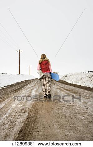 Stock Image - Walking carrying snowboard and boots. Fotosearch