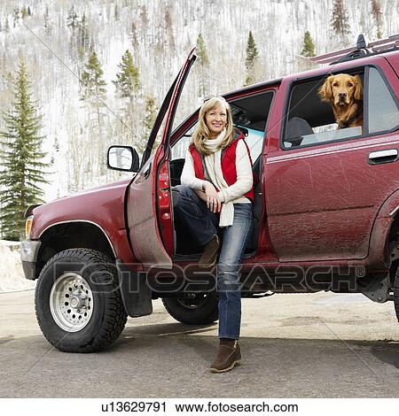 Stock Image - Woman sitting in SUV with dog . Fotosearch