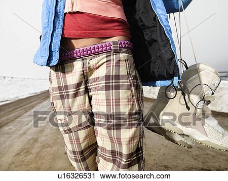 Young woman in winter clothes standing on muddy dirt road holding snowboard and boots View Large Photo Image Stock Image - Young woman in winter clothes standing on muddy dirt road holding snowboard and boots. Fotosearch