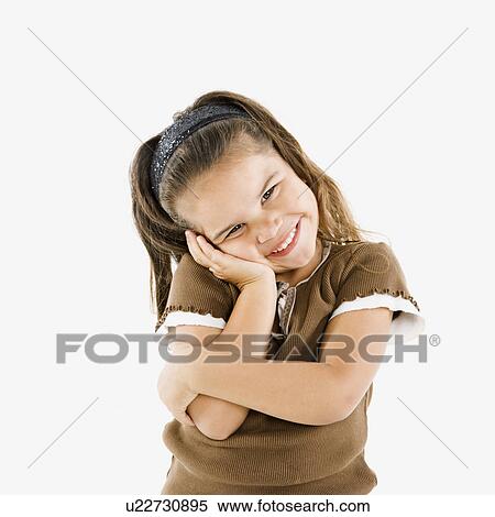 Stock Photography - Adorable little hispanic girl standing smiling with cheek in hand.. Fotosearch