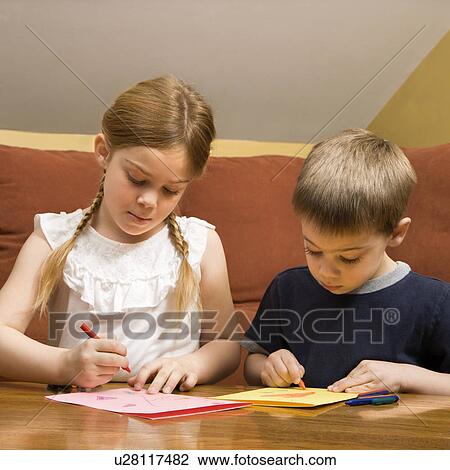 Stock Image - Caucasian boy and girl drawing on paper with crayons.. Fotosearch