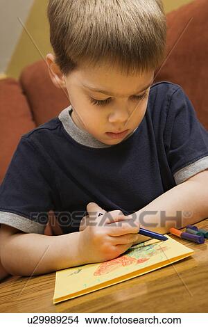 Caucasian boy drawing on yellow paper with crayons. View Large Photo Image Picture - Caucasian boy drawing on yellow paper with crayons.. Fotosearch