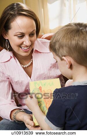 Caucasian boy giving mid adult mother a drawing. View Large Photo Image Stock Photo - Caucasian boy giving mid adult mother a drawing.. Fotosearch