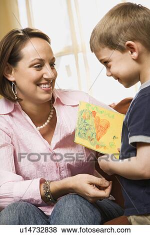 Stock Photo - Caucasian boy giving mid adult mother a drawing.. Fotosearch