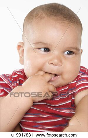 Stock Image - Close-up of cute little hispanic baby boy with fingers in mouth.. Fotosearch