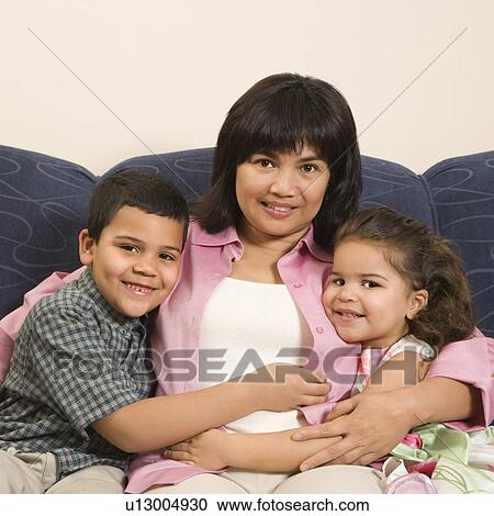 Family sitting on couch hugging each other smiling and looking at viewer. View Large Photo Image Stock Image - Family sitting on couch hugging each other smiling and looking at viewer.. Fotosearch