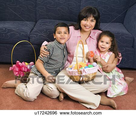 Stock Photograph - Family sitting on floor with Easter baskets smiling and looking at viewer.. Fotosearch