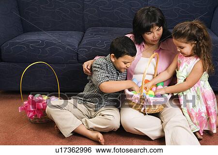 Stock Photograph - Family sitting on floor with Easter baskets.. Fotosearch