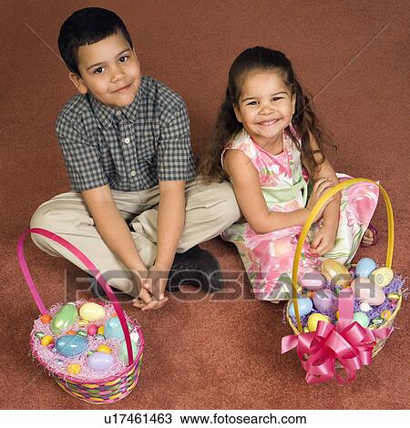 Hispanic brother and sister sitting on floor with Easter baskets looking up at viewer smiling. View Large Photo Image Stock Image - Hispanic brother and sister sitting on floor with Easter baskets looking up at viewer smiling.. Fotosearch